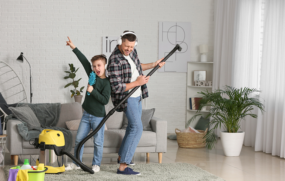 Father and son singing as they clean living room